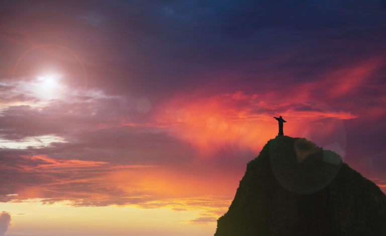 A statue above the mountain during a sunset